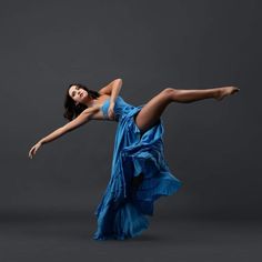 a woman in a blue dress is doing a dance pose with her legs spread out