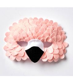 a pink and black mask with feathers on the face, made out of felt material