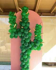 a cactus made out of green grapes on a pink wall