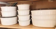 several white dishes are stacked on top of each other in a kitchen cupboard with no one around them