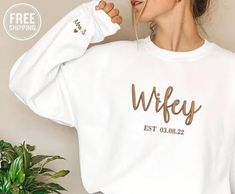 a woman wearing a white sweatshirt with the word wife printed on it in gold ink