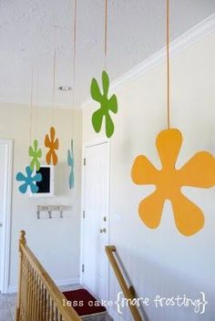 some paper flowers hanging from the ceiling in a room with white walls and wood railings