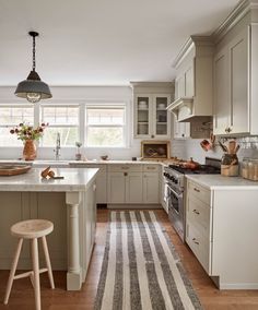 a kitchen with white cabinets and an area rug in front of the stove top oven