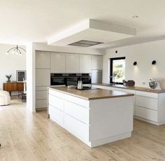 a large kitchen with white cabinets and wood floors