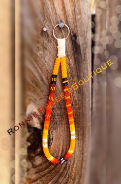 an orange and yellow beaded necklace hanging from a wooden hook on a fence post