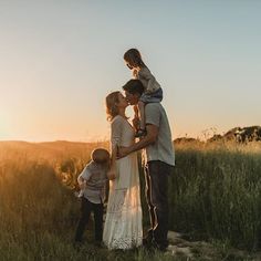 a family is standing in the grass with their little boy and his mother at sunset