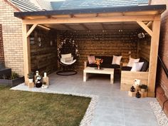 an outdoor living area with wooden furniture and plants on the side of the building,