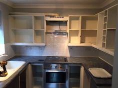 an empty kitchen with white cabinets and gray counter tops, is pictured in this image