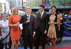 two men and a woman are standing in front of a group of people on the street