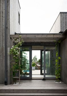 an entrance to a house with wooden steps and plants growing on the side of it