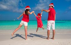 a man and two women in santa hats are playing on the beach