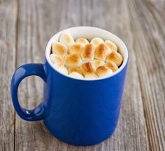 a blue cup filled with hot chocolate on top of a wooden table