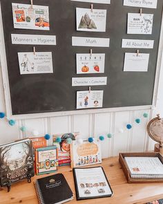 there are many books on the desk with writing paper attached to the wall behind them