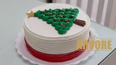 a white cake with green frosting and a red stripe around the bottom that has a christmas tree on it