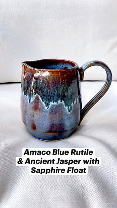 a blue and brown coffee mug sitting on top of a white couch with the words anaco blue ruttle & ancient jasper with sapphire float