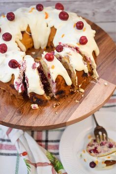 a cake with white frosting and cherries is on a wooden platter