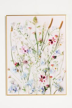 an art piece with flowers on it and some stems sticking out of the top right corner