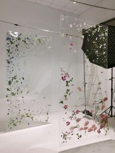 a photo studio with flowers on the wall and an umbrella in front of two glass walls