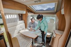 a man and woman are standing in the inside of a camper looking at paperwork