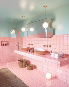 a bathroom with pink and blue walls, two sinks in the center and three mirrors above it