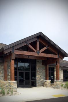 the front entrance to a building with stone pillars and wood beams on it's sides