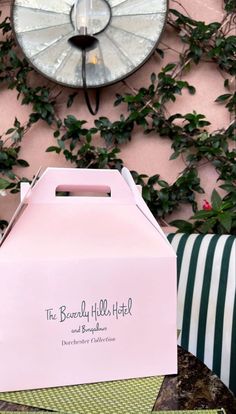 a pink box sitting on top of a table next to a wall with green plants