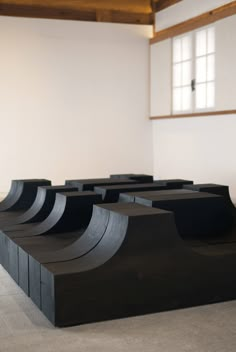 several black skateboard ramps in an empty room