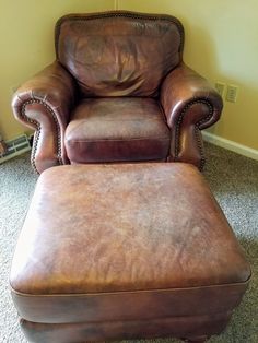 a brown leather chair and foot stool in a room with carpeted flooring on the floor