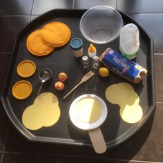 an assortment of crafting supplies are arranged on a black tray with yellow and white circles