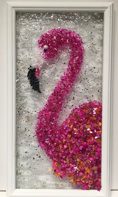 a pink flamingo is in a white frame with confetti on the floor