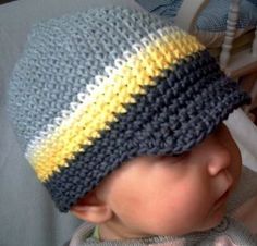 a baby wearing a crocheted hat with yellow and gray stripes