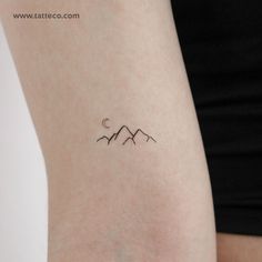 a woman's arm with a small mountain tattoo on the back of her left arm