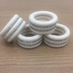 four white and silver beaded rings on top of a wooden table