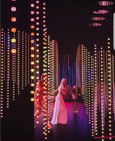 two women in white dresses are dancing on stage with lights all around them and hanging from the ceiling