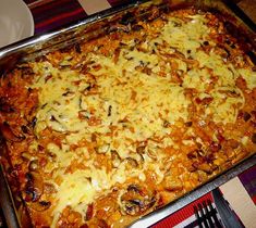 a casserole dish with cheese and mushrooms in it sitting on a tablecloth