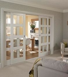 a living room filled with white furniture and lots of glass sliding doors that open up to a dining area