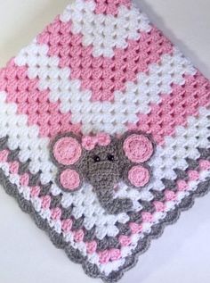 a crocheted blanket with a pink and gray elephant on the front is shown