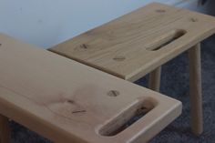 two wooden stools sitting next to each other on carpeted floor with white walls in the background