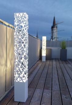 a tall white lamp sitting on top of a wooden floor next to a fenced in area