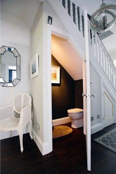 an open door leading to a bathroom with a toilet and chair in the hallway next to it