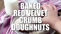 a person holding a doughnut in front of a glass of milk with the words baked red velvet crumb doughnuts