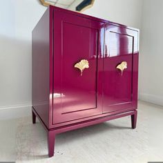 a purple cabinet with gold handles in front of a mirror and clock on the wall