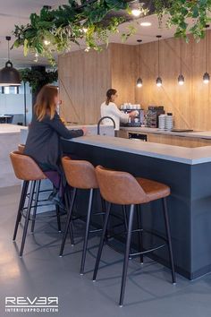 a woman sitting at a bar in front of a counter with three stools next to it