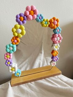 a wooden stand holding a mirror decorated with colorful candy beads and bead work on it