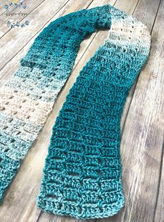 a blue and white crocheted scarf laying on top of a wooden floor