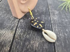 "These gorgeous dangle earrings feature genuine off-white sliced moneta cowrie shells dangling beneath 20mm round carved black and gold acrylic beads an etched Afrocentric abstract pattern. Aching for acrylics? Check out the rest of my acrylic jewelry here: https://etsy.me/2IadiWZ Throughout Africa and the Americas, cowrie shells have historically been viewed as symbols of womanhood, fertility, and prosperity. Check out my other cowrie shell jewelry here: https://etsy.me/2VQS0r0 These earrings m Black Dangle Jewelry For Beach, Unique Black Beach Jewelry, Handmade Black Earrings For Beach, Black Shell Jewelry For Gifts, Black Shell Jewelry Gift, Black Shell Jewelry As A Gift, Handmade Black Jewelry For Beach, Handmade Black Jewelry For The Beach, Handmade Black Jewelry For Vacation