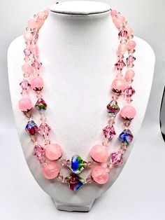 This vintage necklace is a stunning piece of art that will elevate any outfit. It features two strands of pink lucite and art glass beads, along with AB rondelle beads for added sparkle. The necklace has a beautiful multicolor main stone and is perfect for women who love beaded jewelry with an artistic touch. Crafted from high-quality glass and lucite materials, this necklace is a unique addition to any jewelry collection. Its country of origin is unknown, but its beauty is undeniable. Whether you're dressing up for a formal occasion or adding a touch of vintage flair to your everyday look, this necklace is sure to make a statement. Pink Glass Jewelry With Colorful Beads, Pink Glass Necklace With Colorful Beads, Pink Glass Jewelry With Faceted Beads, Pink Czech Glass Necklaces With Colorful Beads, Adjustable Double Strand Pink Jewelry, Vintage Pink Single Strand Jewelry, Pink Czech Glass Necklaces With Faceted Beads, Pink Glass Beaded Necklaces, Pink Beaded Glass Necklaces