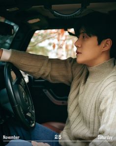 a man sitting in the driver's seat of a car with his hand on the steering wheel