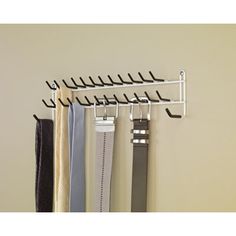 four belts hanging on a wall with hooks and clips attached to it's sides