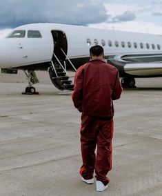 a man in red is walking towards an airplane on the tarmac with it's door open